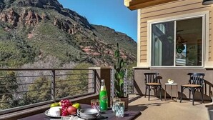 Un balcón con una mesa lista para comer, con vistas a un paisaje montañoso.