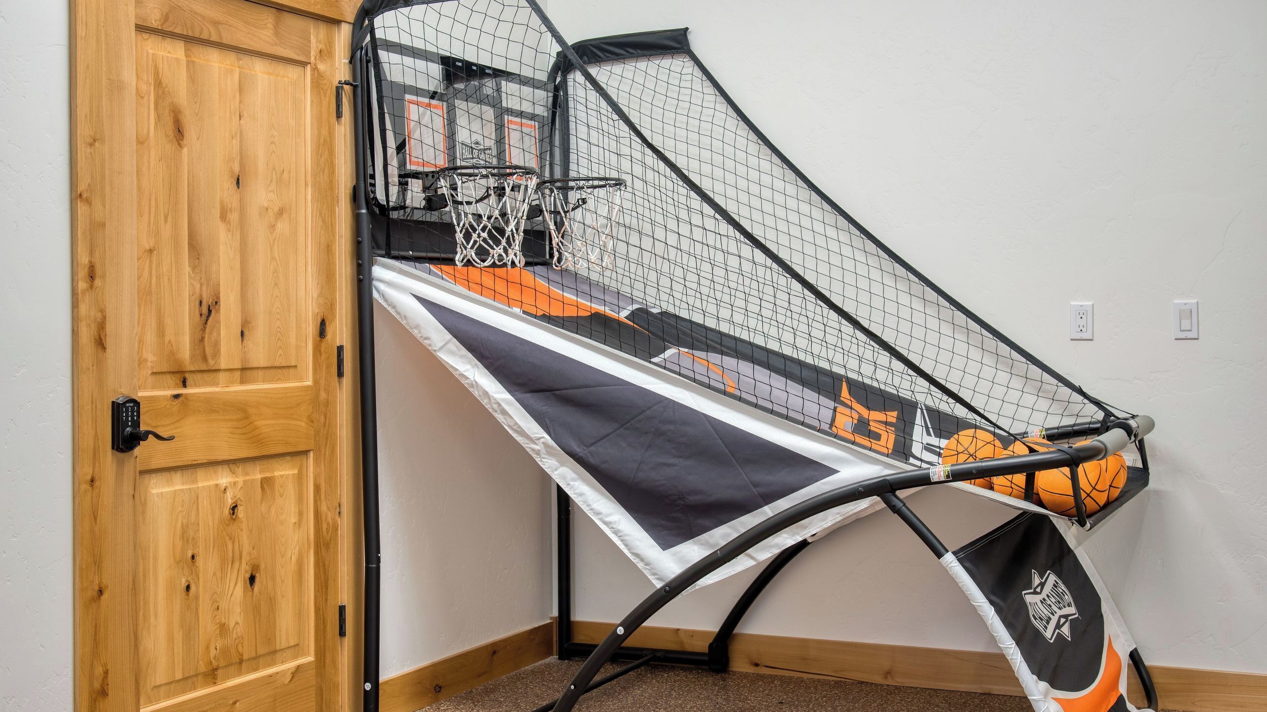 Un aro de baloncesto con red, una puerta de madera y una pared con toma de corriente.