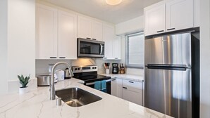 Una cocina moderna con armarios blancos, electrodomésticos de acero inoxidable y encimera de mármol.