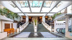 Eine Hotelhalle mit einer zentralen Treppe, einer Rezeption und einer Glaskuppel.