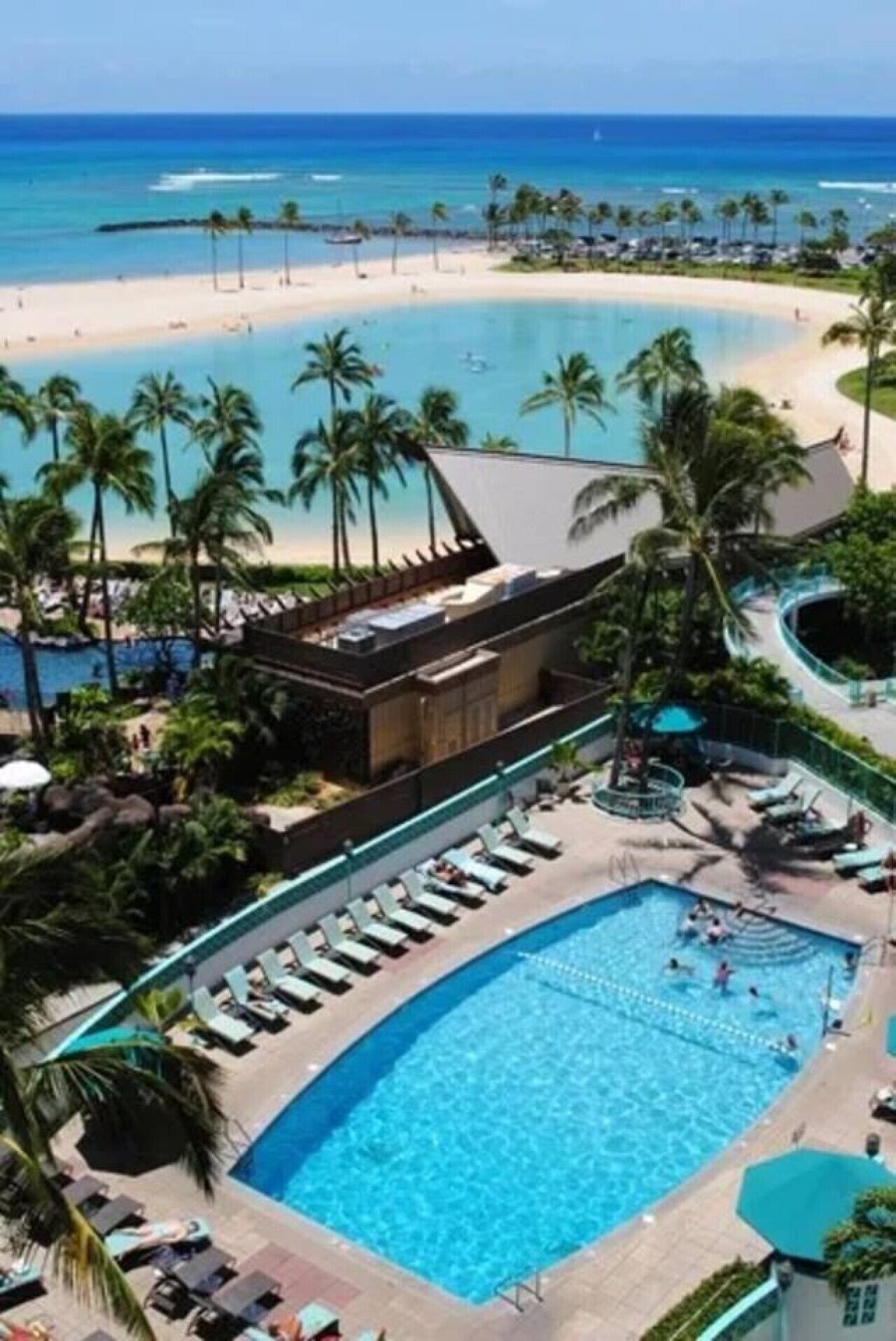 A resort with a large pool, palm trees, and a beach.