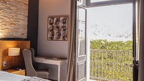 Un dormitorio con cama, escritorio, silla y un ventanal con cortinas.