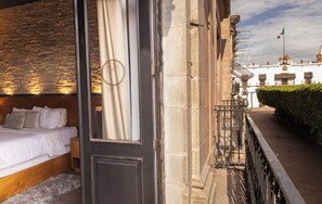 Une chambre d’hôtel avec un lit, une tête de lit en bois et un mur en pierre.