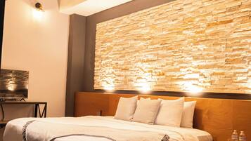 Un dormitorio moderno con una cama grande, una pared de piedra y suelo de madera.
