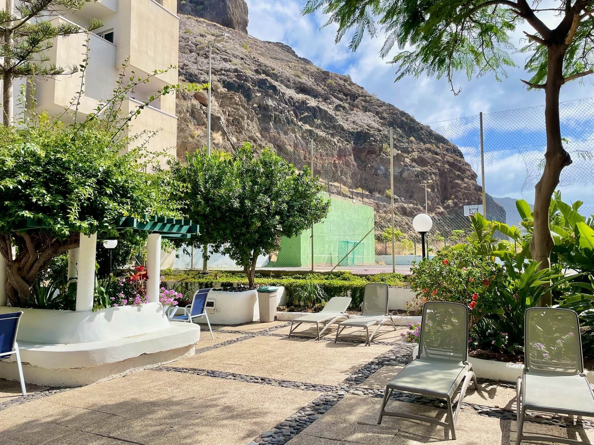 Un área de patio con sillones de descanso, una pequeña fuente y vistas a un paisaje montañoso.
