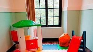A playroom with a table, chairs, a playhouse, and a slide. - Pousada Bom Jesus (Aparecida)