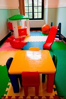 Una sala de juegos con una mesa, sillas, una casita y un tobogán.