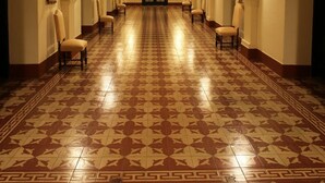A long hallway with patterned floor tiles, chairs along the sides, and wall-mounted lights. - Pousada Bom Jesus (Aparecida)