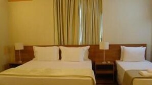 A hotel room with a large bed, two smaller beds, a nightstand with a lamp, and a window with curtains. - Pousada Bom Jesus (Aparecida)