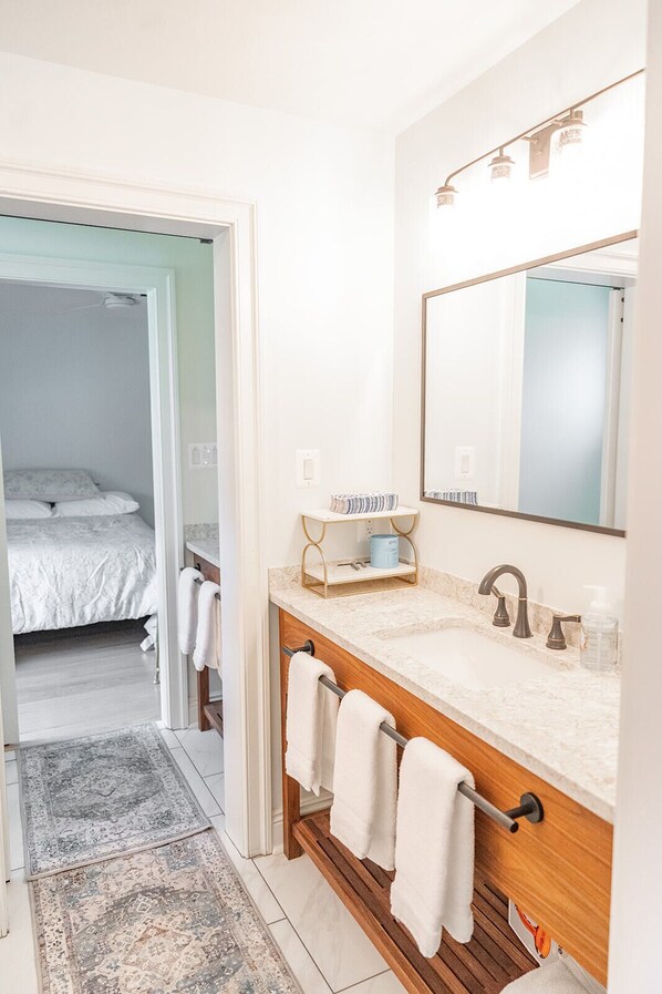 A modern bathroom with a large mirror, a wooden vanity, and a walk-in shower.