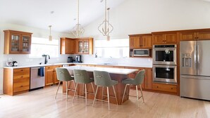 Een moderne keuken met houten kastjes, roestvrijstalen apparatuur en een centraal eiland met barstoelen.