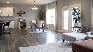 Un grand espace de vie comprenant une table à manger, un canapé et une cuisine en arrière-plan.