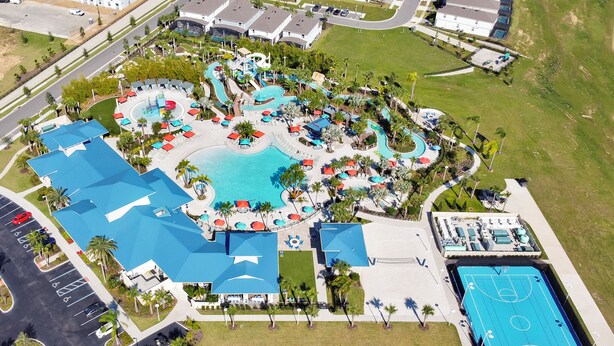 Luchtbeeld van een resort met een centraal zwembad, meerdere loungegedeeltes en een basketbalveld.