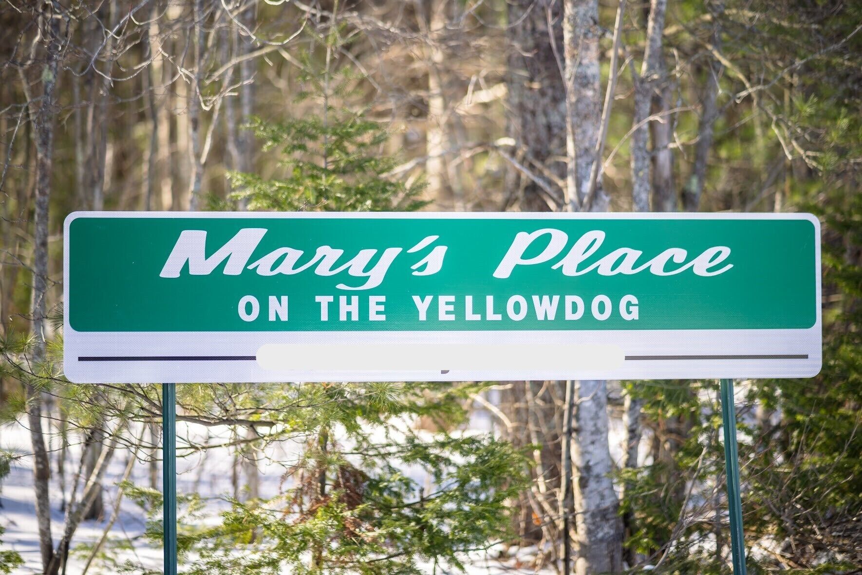 Ein Schild mit der Aufschrift 'Mary's Place ON THE YELLOWDOG' auf gelbem Hintergrund und weißer Schrift.