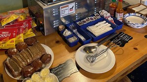 Un bufé de desayuno con diversas opciones de comida, un tostador, salsas y un letrero dando la bienvenida a los huéspedes para disfrutar del desayuno.