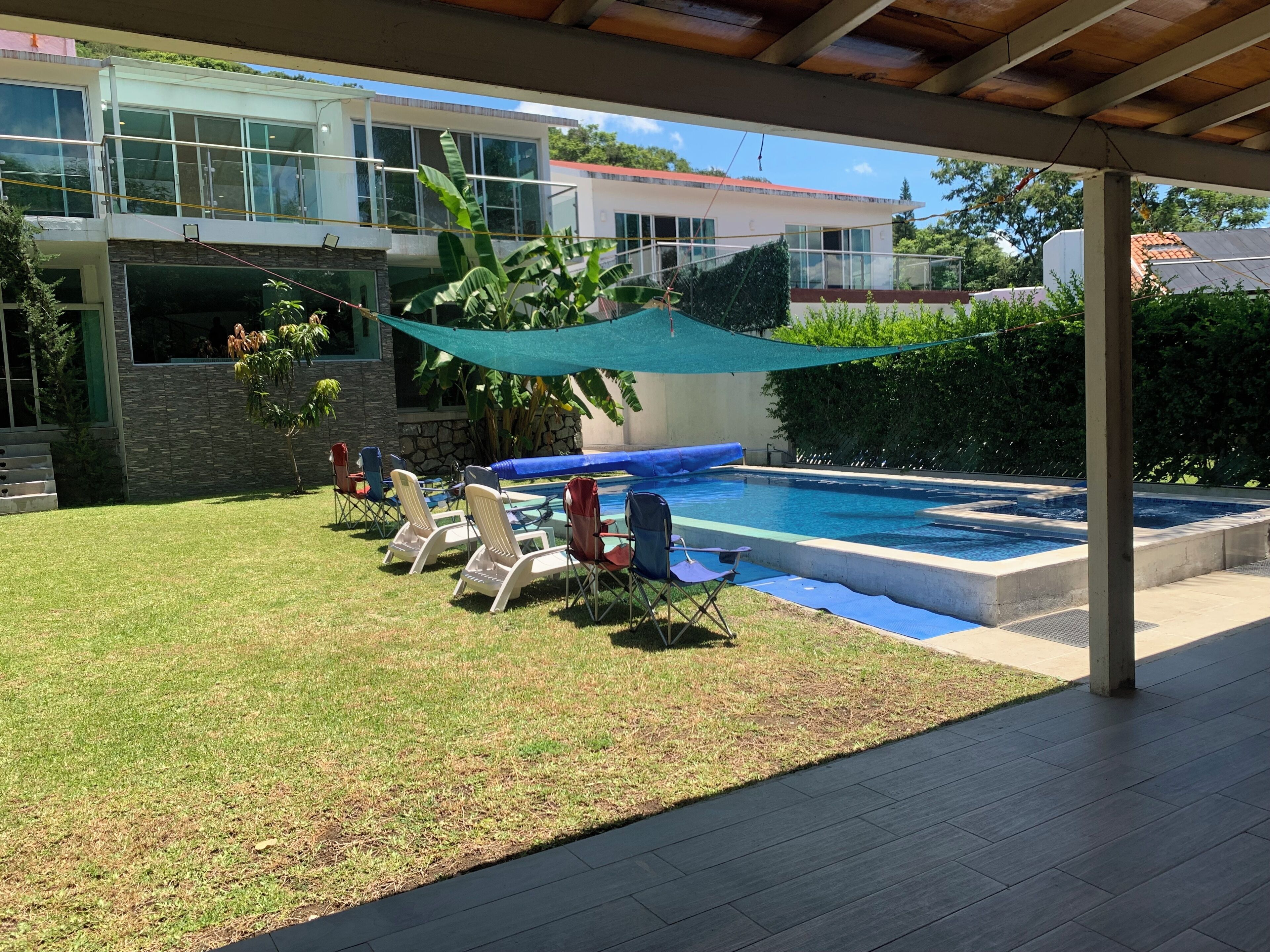 Une maison moderne dotée d’une piscine, d’un patio couvert et d’un espace salon extérieur.