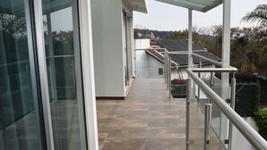 Een modern gebouw met een glazen gevel, een overdekte doorgang en een metalen hekwerk.