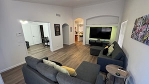 A modern living room with a grey sectional sofa, a small round table, and a flat-screen TV. - Charming 3-bedroom house upscale neighborhood with WiFi, AC in awesome Glendale (Glendale)
