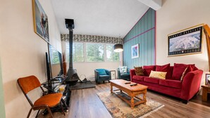 Una sala de estar con chimenea, un sofá rojo, una mesa de centro de madera y un sillón azul.