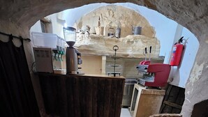 A rustic kitchen with a stone archway, wooden furniture, and basic amenities.