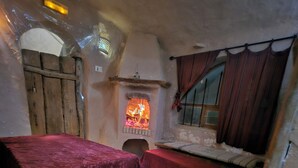 A rustic room with a stone fireplace, wooden furniture, and a bench.