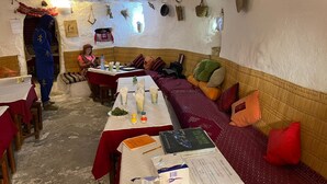 An ice hotel interior with tables set for dining, a person in a blue costume, and various decorative items on the walls.