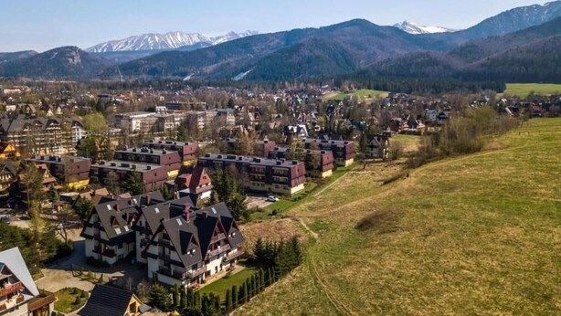 Una zona residencial con casas tradicionales, un pequeño centro urbano y montañas al fondo.