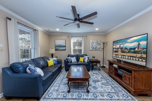 Cozy living room with leather sofas, 65" smart TV, fan & board games for fun.