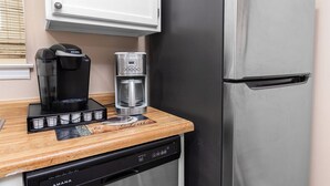 A kitchen with a coffee maker, a water dispenser, and a refrigerator.