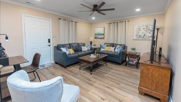 A living room with a sofa set, a coffee table, a TV stand, and a ceiling fan.