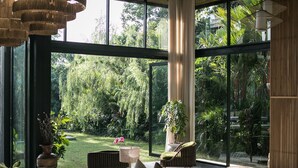 A spacious living area with a large window, a wooden ceiling, and a modern sofa set. - Architect 4 BDR River Villa in Nyanyi Beach (Canggu)