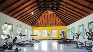 Un gimnasio con cintas de correr, bicicletas estáticas y máquinas de pesas.
