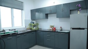 Una cocina moderna con armarios grises, estufa integrada, escurreplatos y refrigerador.
