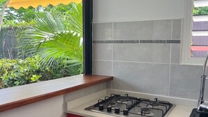 A compact kitchen with a gas stove, a sink, and red cabinets. - BUNGALOW GRENADE (Saint-François)