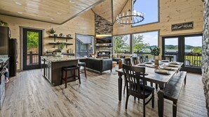 Une cuisine spacieuse avec un grand îlot central, un coin repas avec une table pour quatre personnes et un salon confortable avec un canapé et une cheminée.
