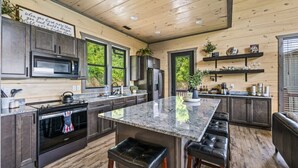 Uma cozinha moderna com bancadas de granito, eletrodomésticos de aço inoxidável e uma ilha grande com banquetas.