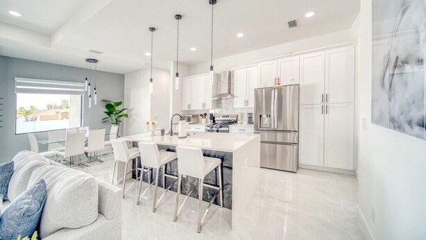 A modern kitchen with white cabinets, stainless steel appliances, and pendant lighting. - Charming 4-bedroom house with Heated Pool (Cape Coral)