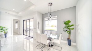 A modern, well-lit conference room with a glass table, white chairs, and potted plants. - Charming 4-bedroom house with Heated Pool (Cape Coral)