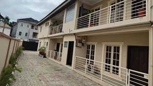 A multi-story residential building with balconies, a tiled courtyard, and a gated entrance. - The Hub Apartment Lekki (Lekki)