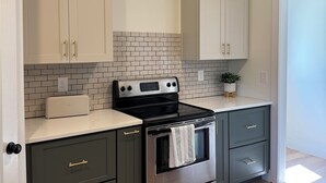 A kitchen with white cabinets, a black stove, and a tiled backsplash.