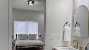 A modern bathroom with a white sink, gold fixtures, and a large mirror.