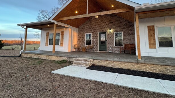 A modern house with a brick exterior, a wooden porch, and a covered patio area.