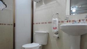 A bathroom with a toilet, a sink, and a towel dispenser. - Hotel Rincon Tarasco (Morelia)