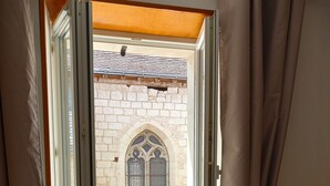 Una habitación con ventana que da a un balcón con suelo de baldosas y pared de piedra.