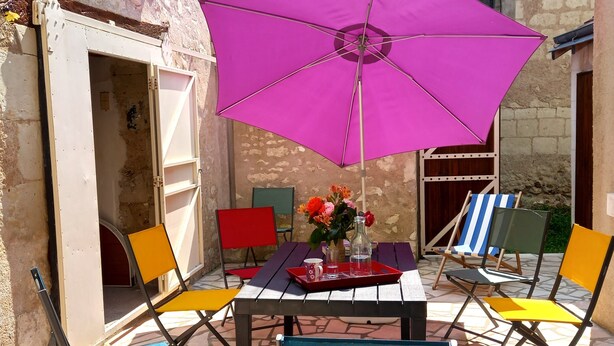 Un patio con mesa, sillas y una sombrilla grande.