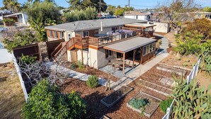 Une maison à deux étages dotée d’un patio, d’une petite terrasse et d’un jardin aménagé avec des plates-bandes surélevées.