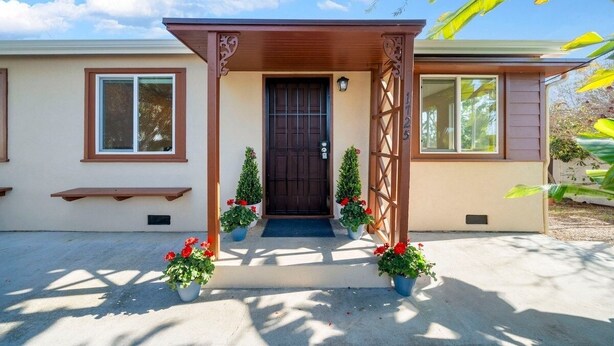 Une maison à deux étages avec un porche à l’avant, une porte de couleur brun foncé et une boîte aux lettres.