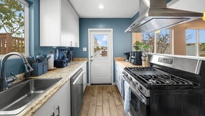 Une cuisine moderne dotée d’une cuisinière en acier inoxydable, de meubles blancs et d’un plan de travail en granit.