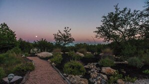 A gravel pathway leading to a metal gate, surrounded by rocks and various shrubs. - Resort Style S/W Home on 3 Acres. Views, Pool, Outdoor Fireplace (Bulverde)