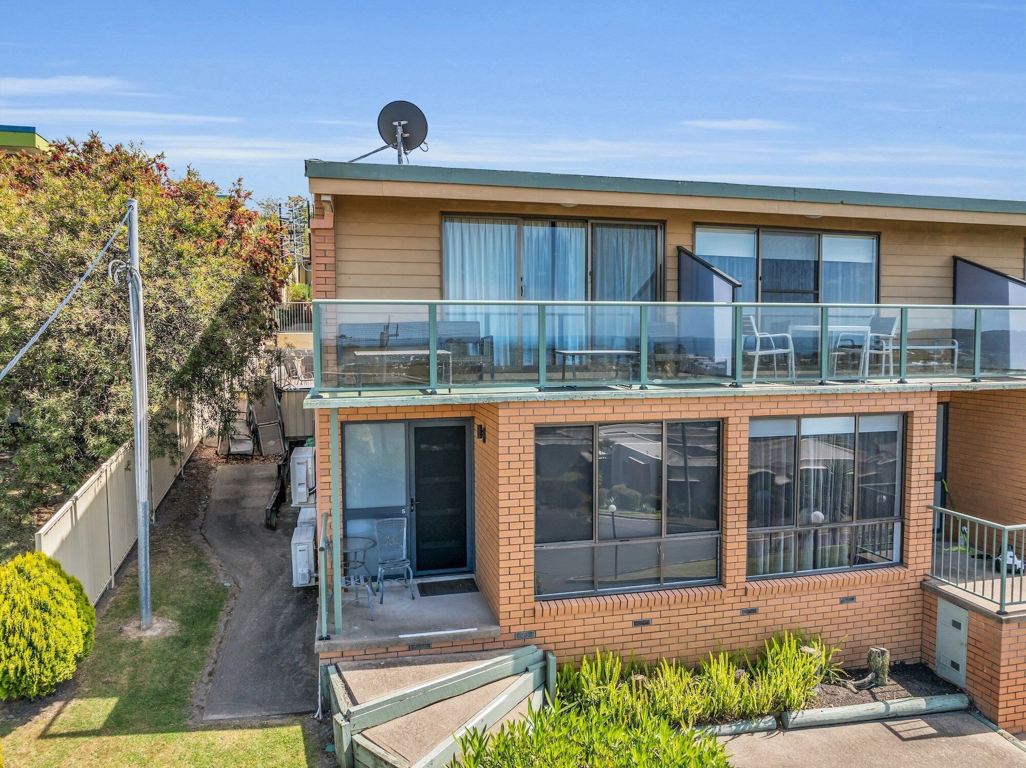 A two-story house with a balcony, large windows, and a satellite dish.